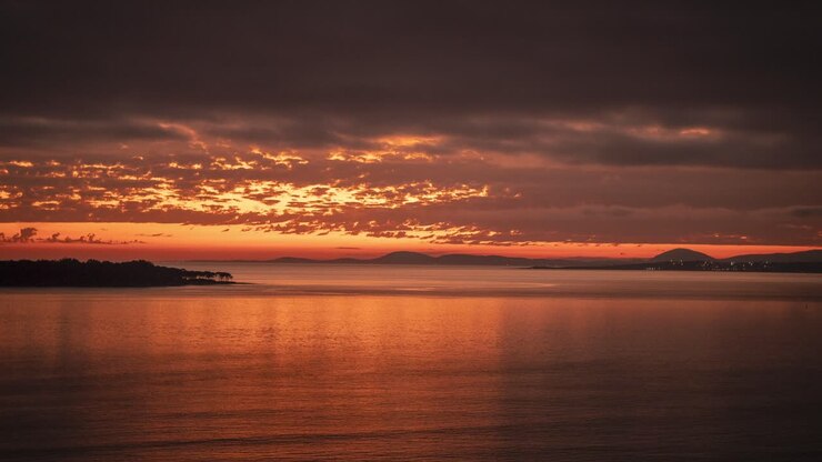 Day to night time lapse of Punta del Este beach at sunset with rippled ocean surface and Gorriti island in background, Uruguay