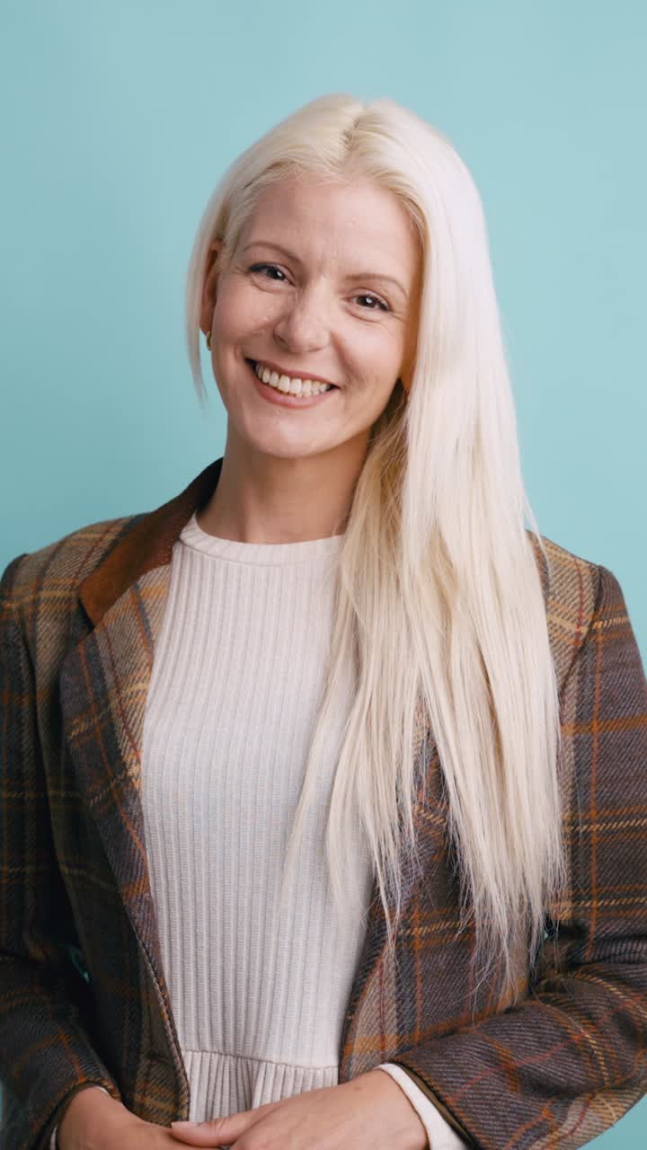 Giovane donna felice con i capelli biondi che sorride alla fotocamera in studio