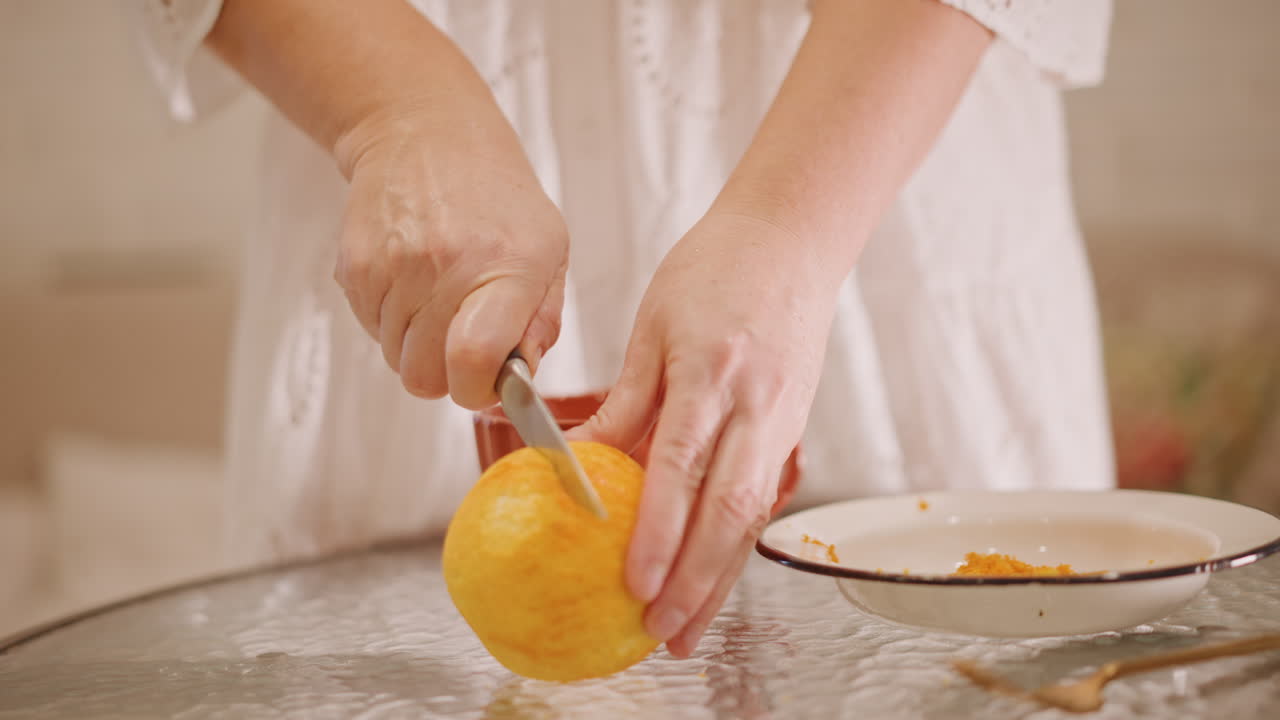 Donna che sbuccia una zucca per la torta, mani ferme su un tavolo infarinato, ciotola vintage tenuta delicatamente, coltello che affetta la buccia, polpa di zucca che si raccoglie in un piatto, luce naturale soffusa, atmosfera di cottura autunnale accogliente