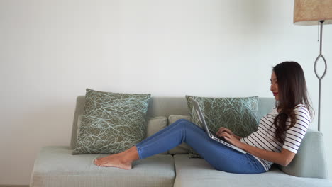 young casual asian woman working on laptop computer while sitting in sofa