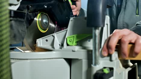 close-up of a man's hand working on a machine with a circular saw