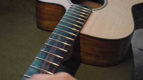 handmade guitar - luthier applying lemon oil cleaner conditioner on the guitar fretboard to clean and moisturize it