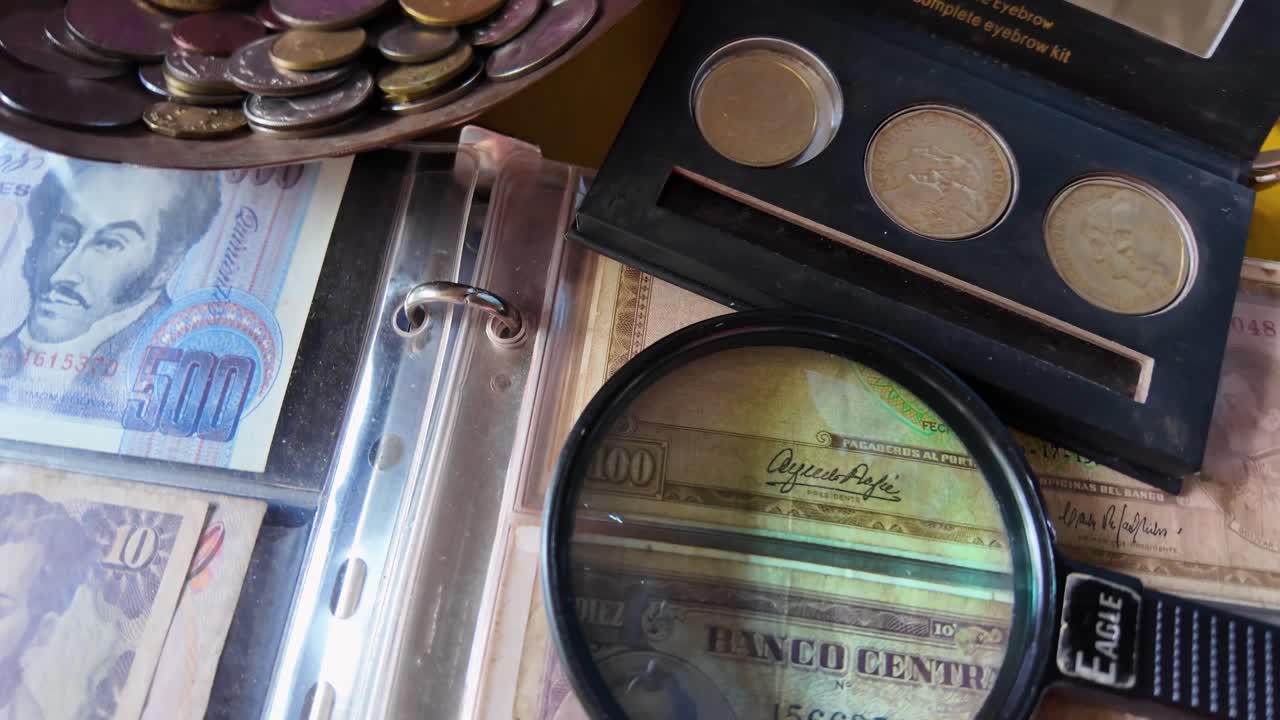 Venezuelan old currency. A magnifying glass used to validate authenticity of venezuelan coins and bills. Person in blurred background
