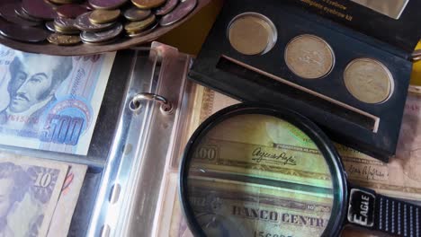 venezuelan old currency. a magnifying glass used to validate authenticity of venezuelan coins and bills. person in blurred background