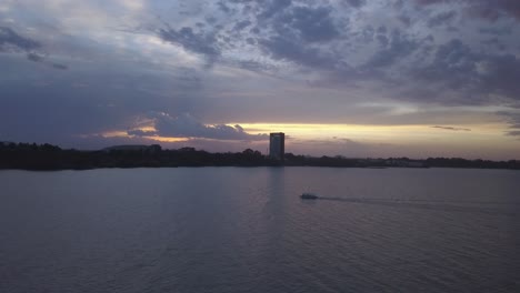a boat is sailing on a lake during sun set.