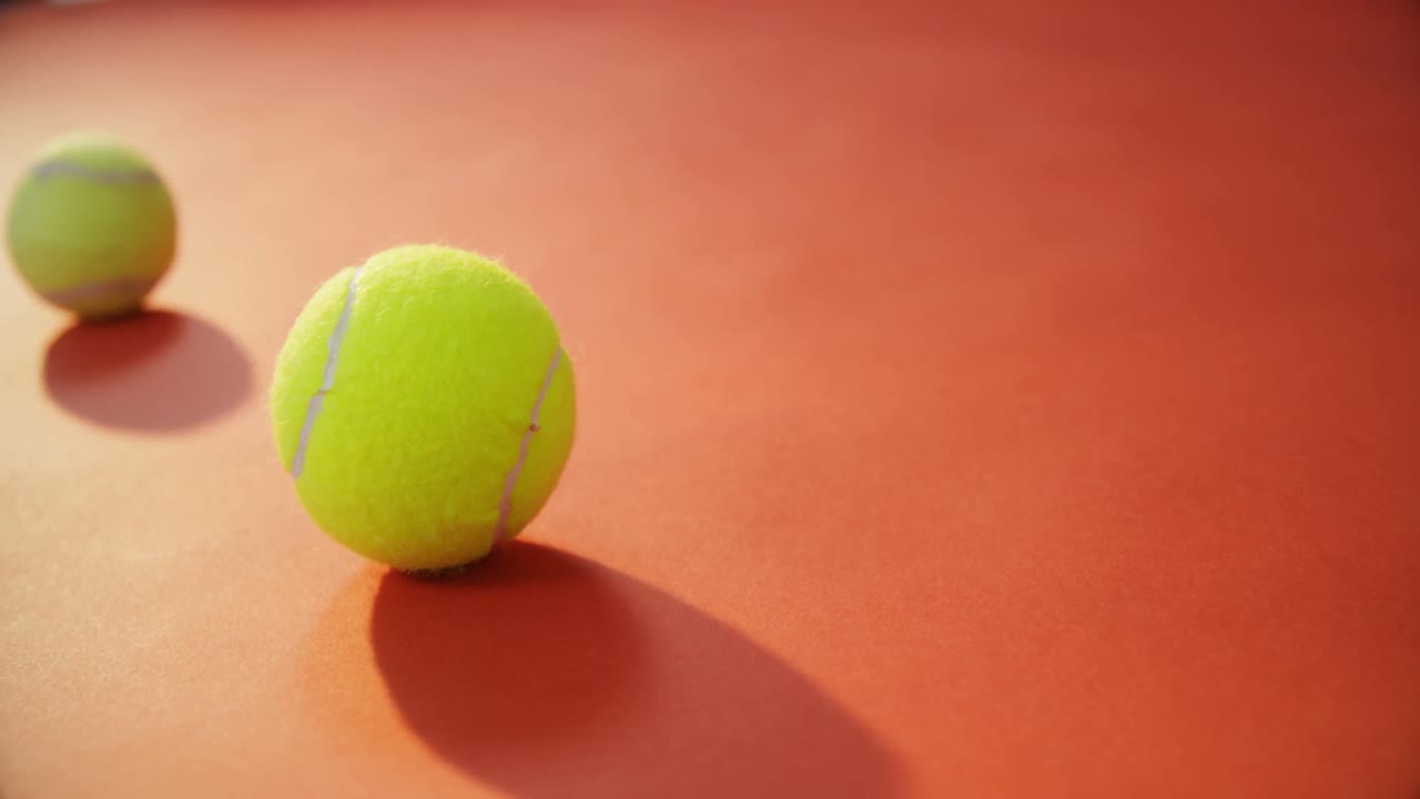 테니스 공이 빨간 바닥에서 뛰고 있습니다.