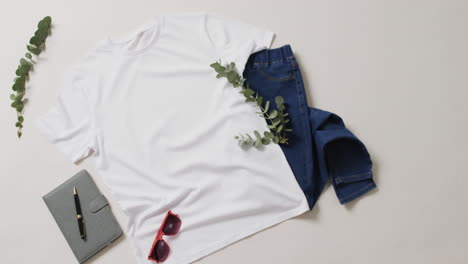video de camiseta blanca, pantalones vaqueros, cuaderno, gafas de sol y espacio de copia sobre un fondo blanco