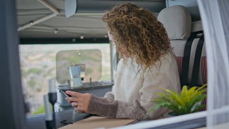 attractive traveller texting smartphone in trailer kitchen closeup. woman typing