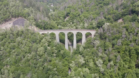 arches of a stone train viaduct over a mountain pass forest,static