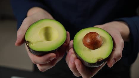 aguacate cortado por la mitad en las manos