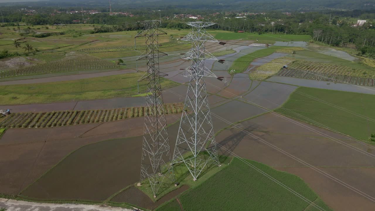 Drone shot of high voltage electric tower in the middle of rice field