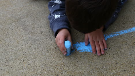 young boy age 4 years old, drawing on sidewalk with chalk