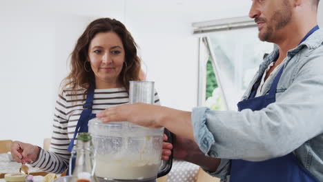 man and woman taking part in kitchen cookery class tasting food