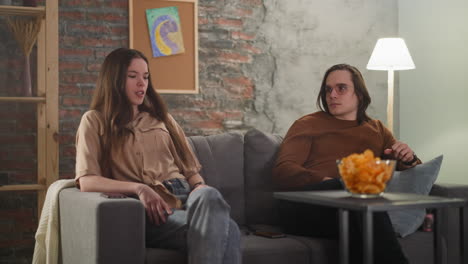 Young-woman-and-long-haired-man-at-sports-game-in-flat