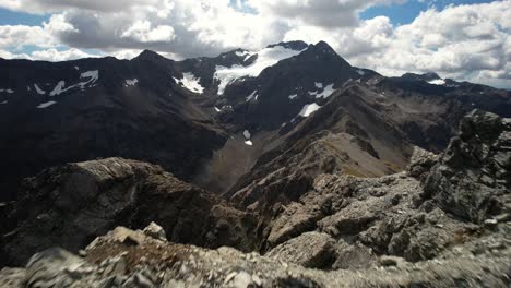 Toma-Dinámica-Aérea-Sobre-La-Cumbre-De-La-Montaña-Rocosa,-Revela-Un-Paisaje-Dramático-Alpino