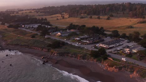 Low-aerial-dolly-shot-of-oceanfront-inns-along-Moonstone-Beach-at-sunset-in-Cambria,-California