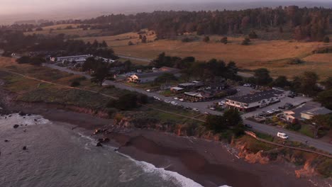 low aerial dolly shot of oceanfront inns along moonstone beach at sunset in cambria, california