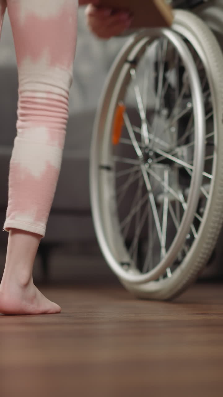 돌보는 딸은 장애를 가진 어머니가 바닥에 누워있는 책을 들을 수 있도록 도와줍니다. 유치원 소녀는 수술 후 체어에서 엄마를 돌보고 있습니다.