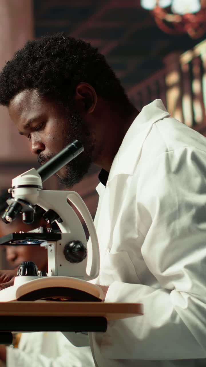 Scienziato afroamericano che osserva al microscopio in laboratorio