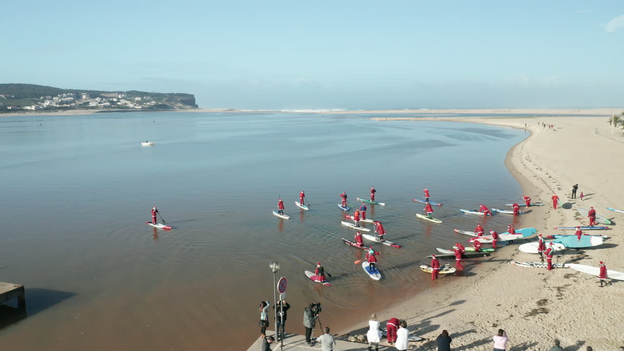 People In Santa Claus Costume Holding Their Paddle Boards Bound To The Waters Of Obidos Lagoon, Portugal