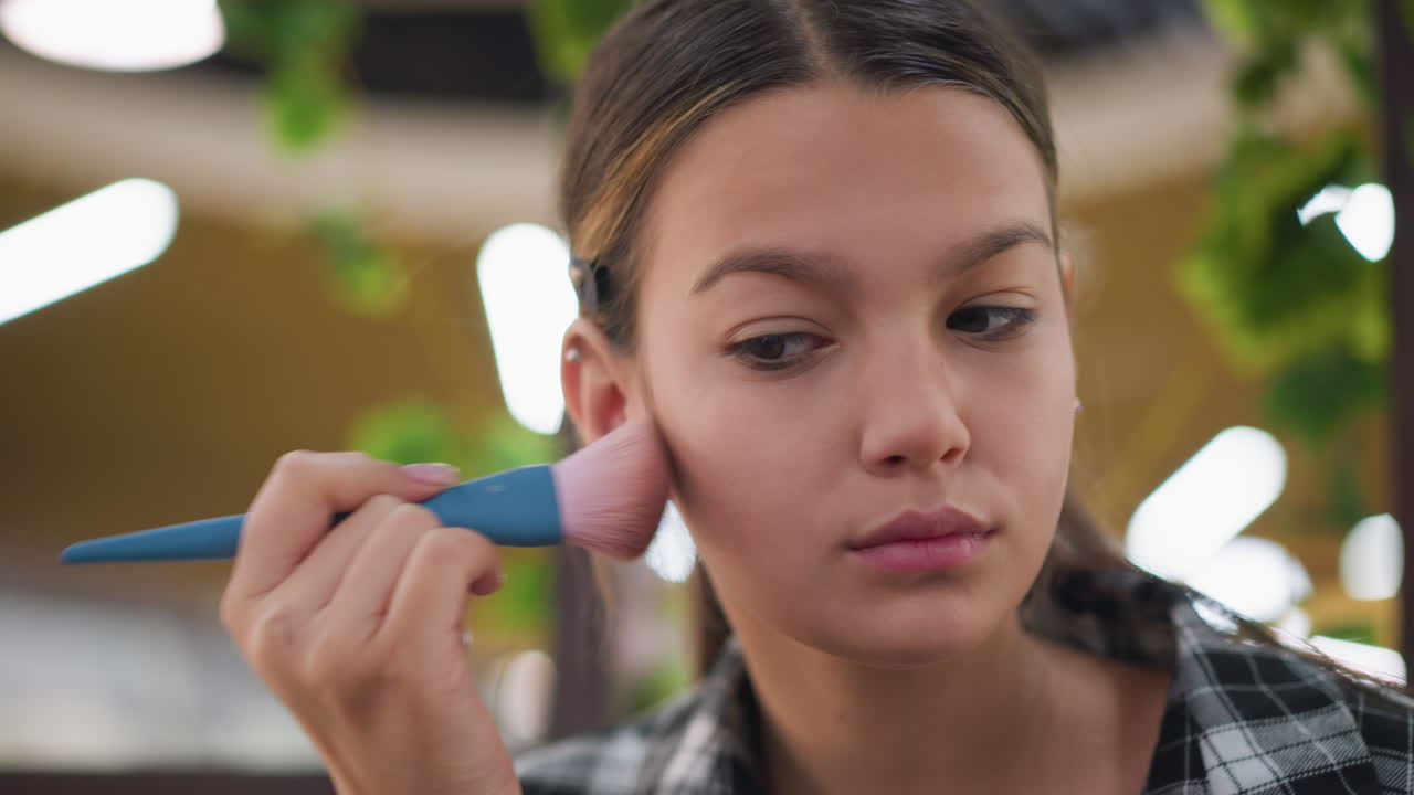 vista de cerca de una joven que limpia las mejillas con un pincel de maquillaje, aplicando rubor para un acabado suave y un brillo saludable en su rostro, centrarse en la técnica de maquilaje y la mejora de la belleza