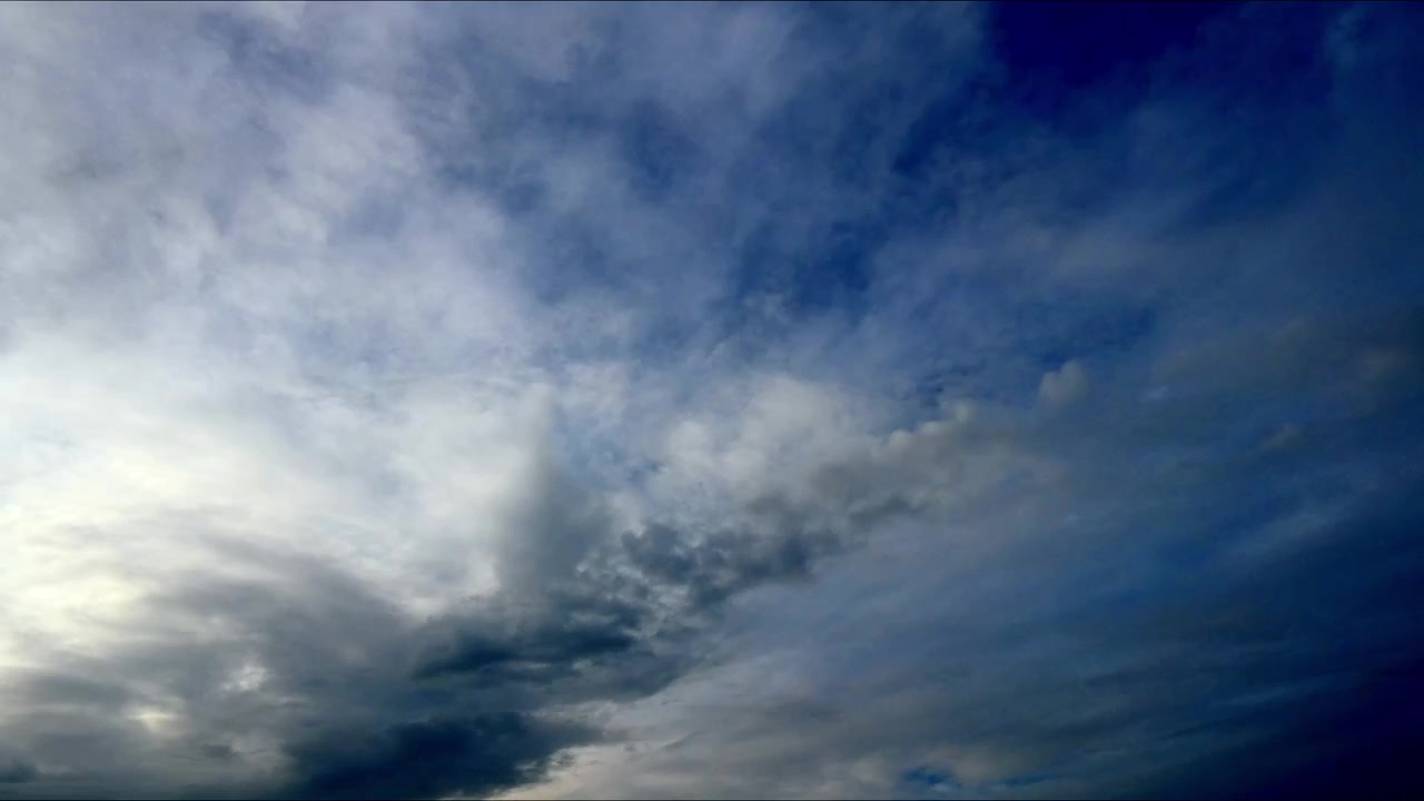Timelapse of clouds drifting across a bright blue sky, showcasing natural atmospheric movement and changing weather in a peaceful outdoor scene.