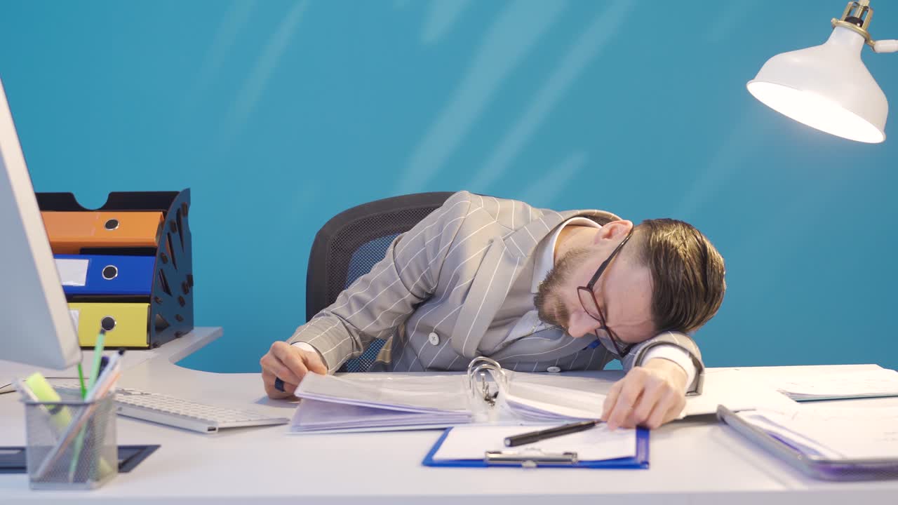 졸린 사업가는 일하는 동안 잠들어 있습니다.