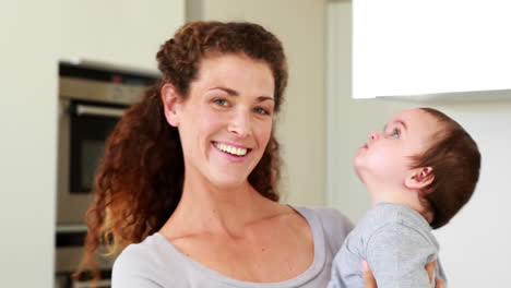 mother holding her happy baby boy smiling at camera