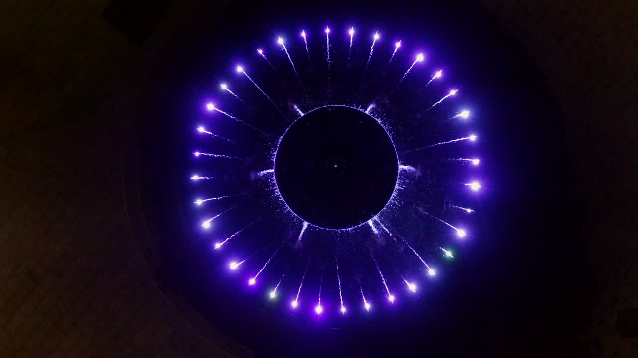 vista superior fuente musical colorida en la oscuridad. agua fluyendo en fuente iluminada en la ciudad oscura. vista de avión no tripulado fuente de baile con iluminación multicolor en la plaza de la ciudad