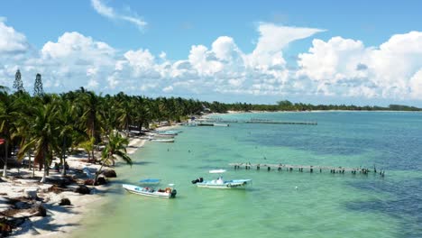 aerial drone dolly in flying shot of a small fishing town in the nature reserve of sian ka'an near tulum, mexico with small fishing boats, piers, palm trees, and white sand on a summer day