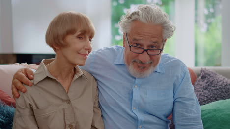 Senior-woman-looking-at-man.-Mature-couple-sitting-on-couch-in-living-room