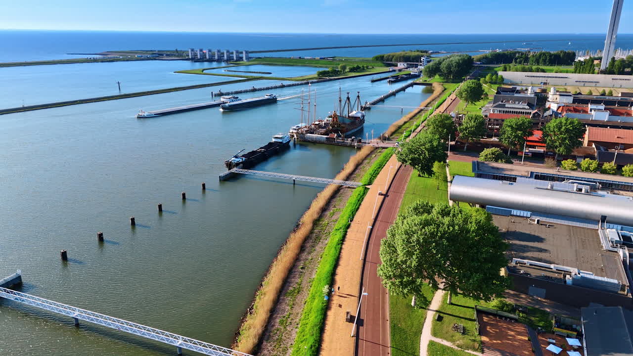 Lakefront of Markermeer lake and dams on it. Drone footage approaching the reconstruction of ship Batavia in the museum Batavialand in Lelystad, the Netherlands.