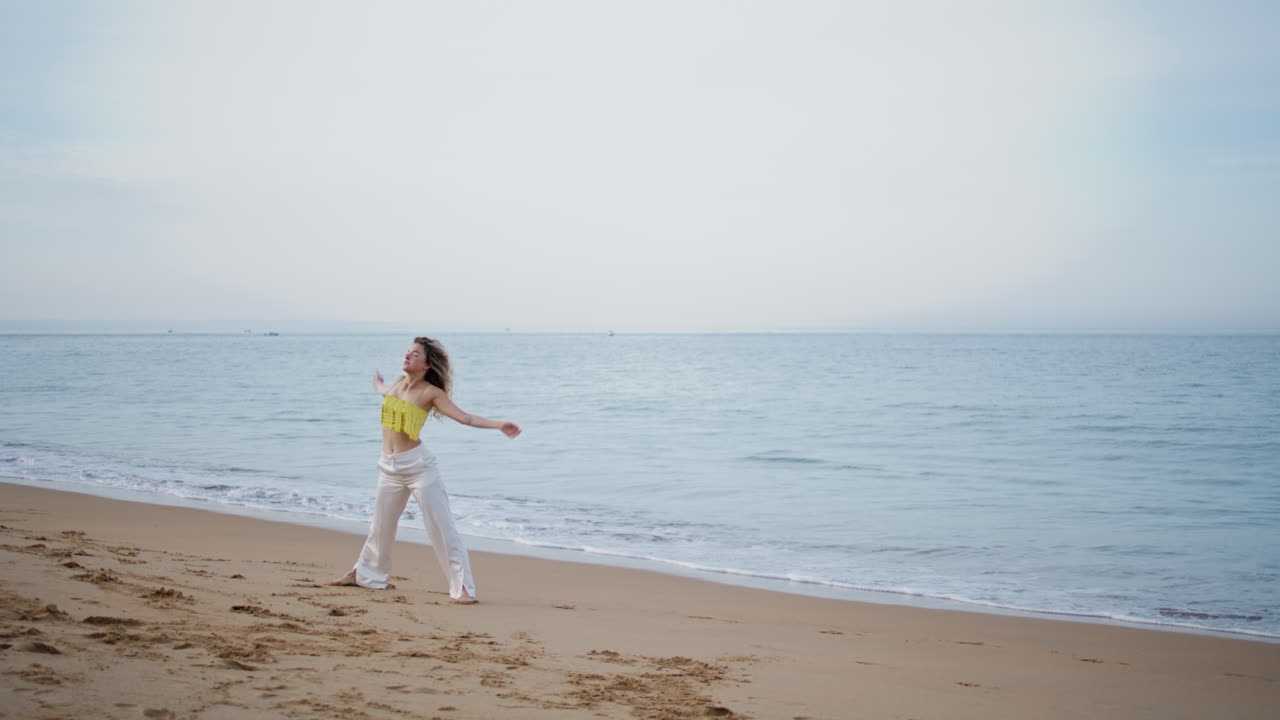 매혹적인 여자가 춤을 추고 있는 해안가 모래를 고 있는 여자 댄서가 현대를 연습하고 있다.