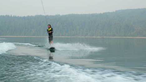 vista frontal de un joven caucásico haciendo trucos en wakeboard en el río de la ciudad 4k