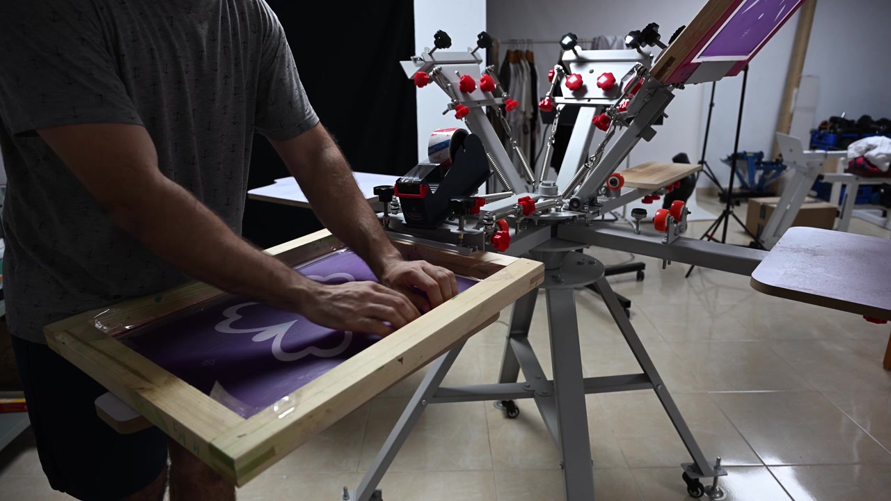 Screen printing porcess. Taping the mesh for stencil print. Preparation of the machinery to screen print on textile.