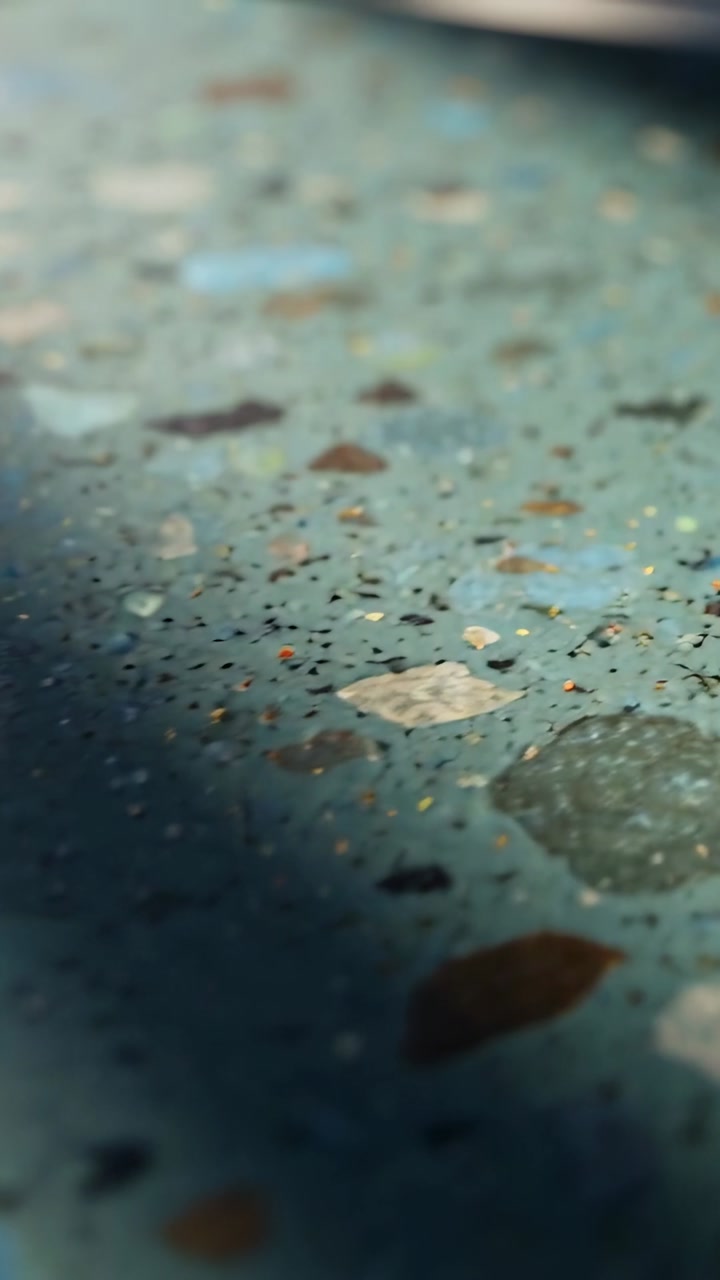 Vertical video: Camera shifting shadow drifting terrazzo showing flecks and metallic rim for design