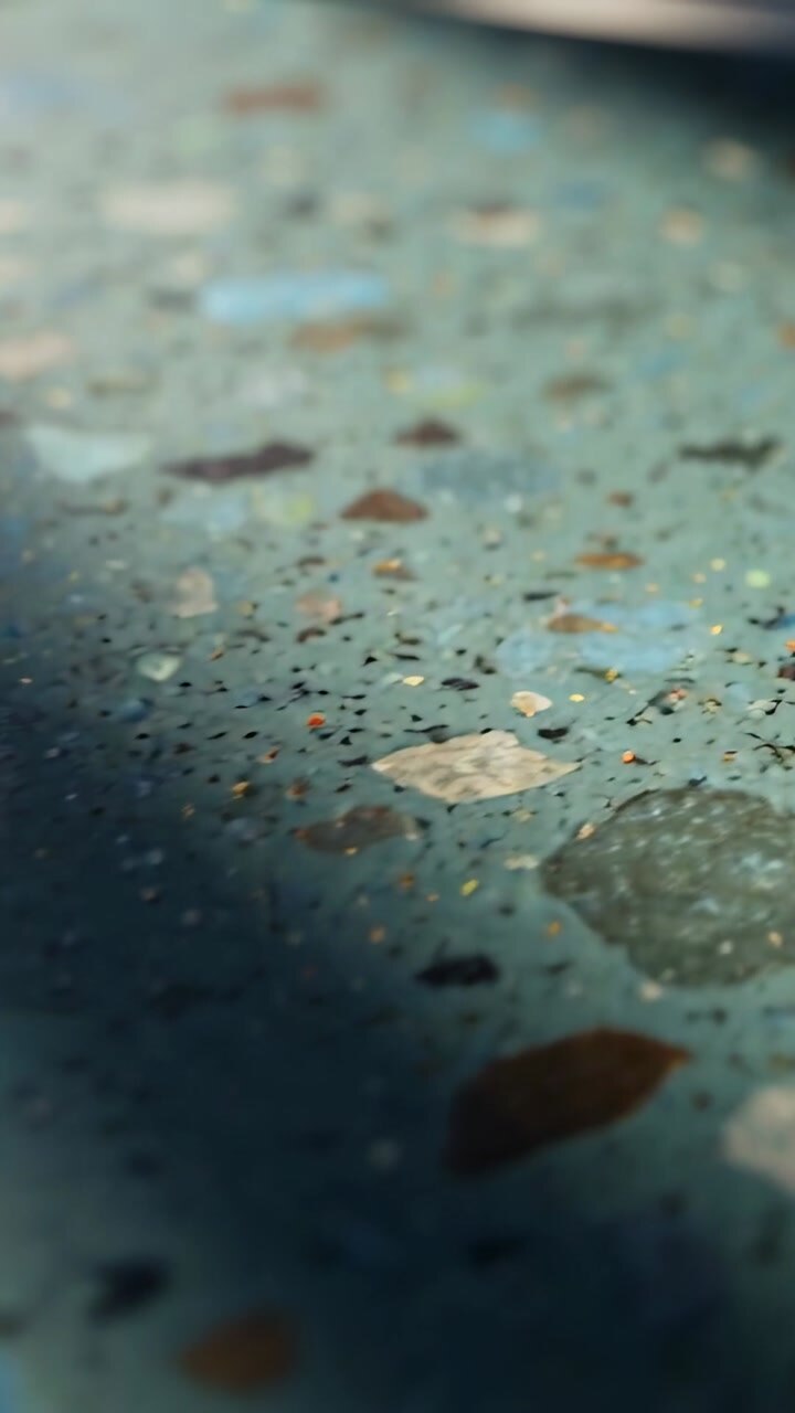 Vertical video: Camera shifting shadow drifting terrazzo showing flecks and metallic rim for design