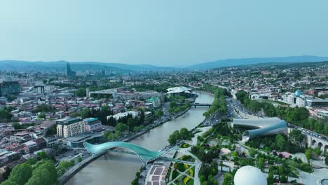 drone disparar para el puente de la paz en georgia tbilisi con un hermoso paisaje de toda la ciudad con cielo despejado y tiempo soleado
