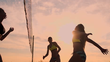 Group-of-young-girls-playing-beach-volleyball-during-sunset-or-sunrise