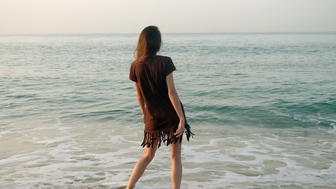 코스타 델 마레스메 해변에서 행복한 예쁜 여자가 칼레야 해변에서 즐거움을 느끼고 모래 해변에서 춤을 추고 지중해의 파도와 놀고 있습니다.