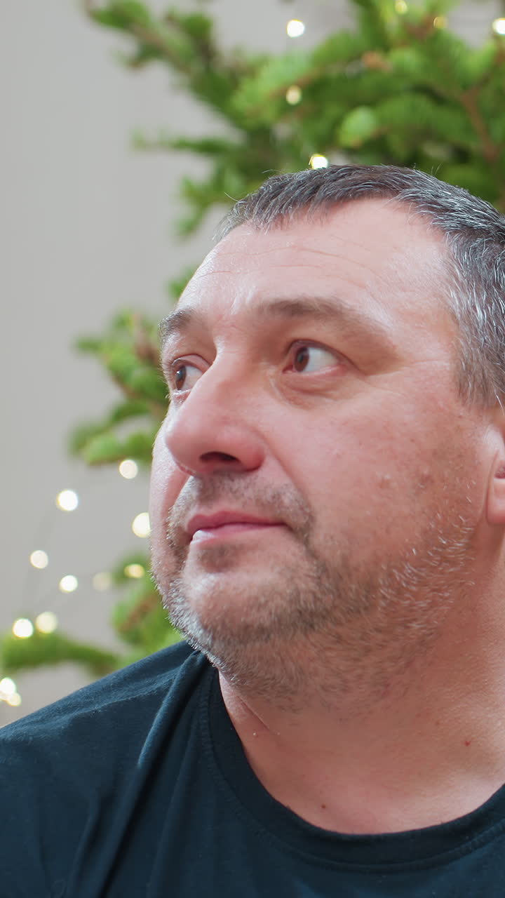 Caucasian man playfully dusted with snow, bright holiday tree bokeh in background sequence captures subtle winks, closedeye pauses, and amused smiles as he behaves like jovial neighbor, impromptu