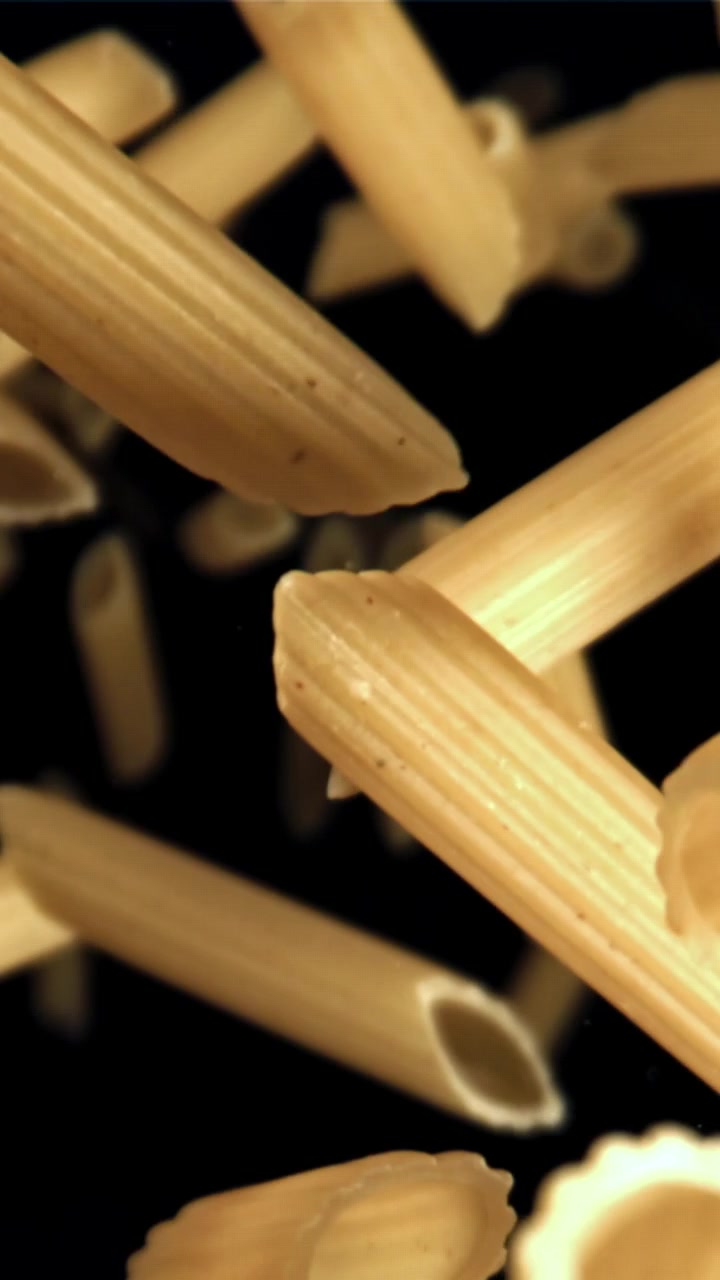 Pasta penne che cade al rallentatore su sfondo nero