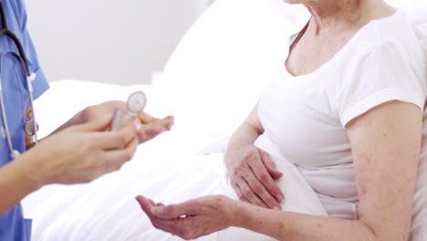 nurse giving pills to senior woman