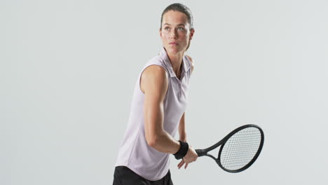 young caucasian woman plays tennis indoors on a white background