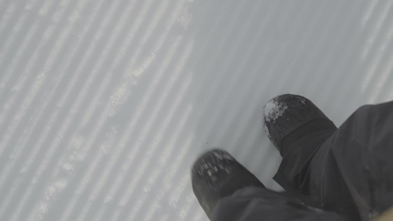Walking on the snow covered prepared slope in ski resort. Snowboard boots walking.