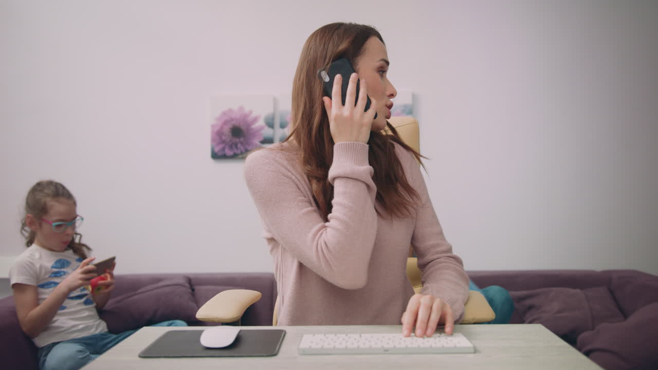 Happy mother talking on the phone at home workplace