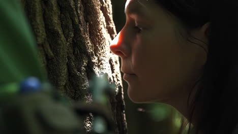woman's profile bathed in sunlight next to a tree trunk
