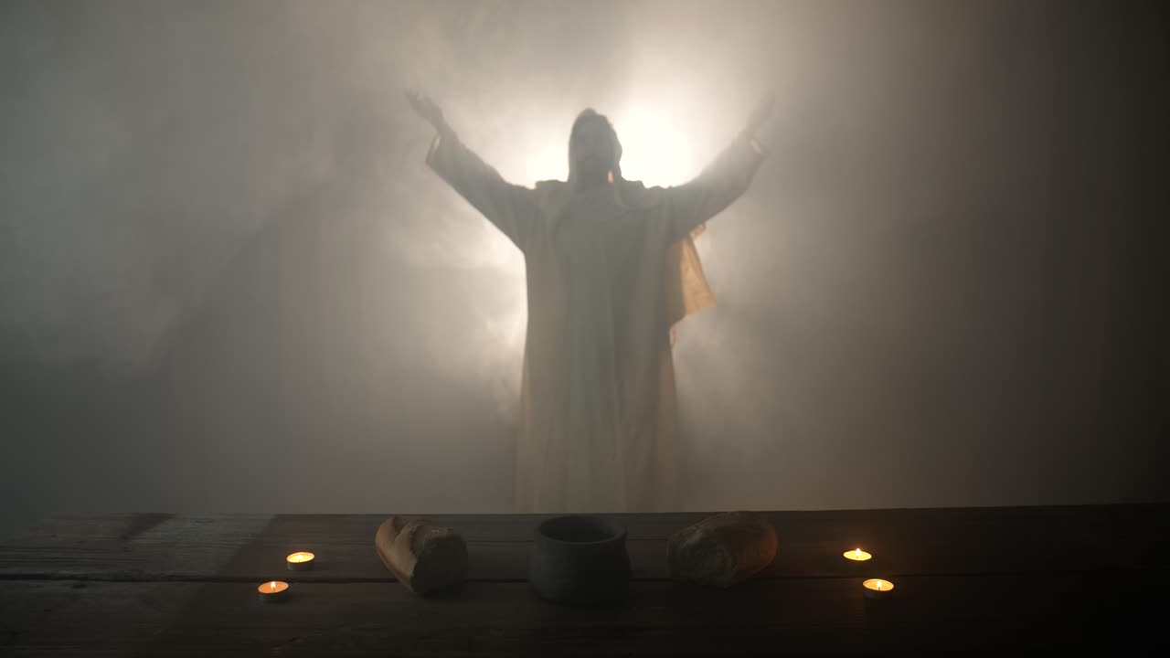 Jesus Christ lifts hands praying, worshipping, standing near a table with Christian sacraments of bread and wine for last supper, communion, cinematic Easter symbolism.
