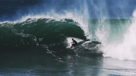 rolling barrel bends light across translucent lip as surfer slices through trough