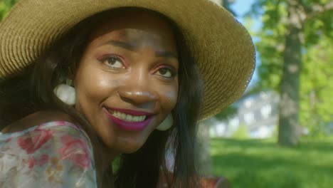 Beautiful-African-American-woman-relaxing,-thinking,-smiling-in-park---sunny-day